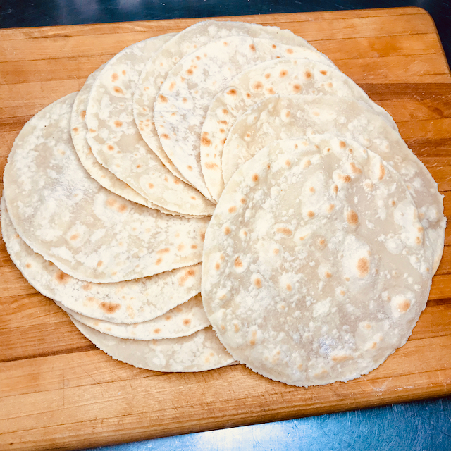 Pile of gluten free tortillas on a cutting board