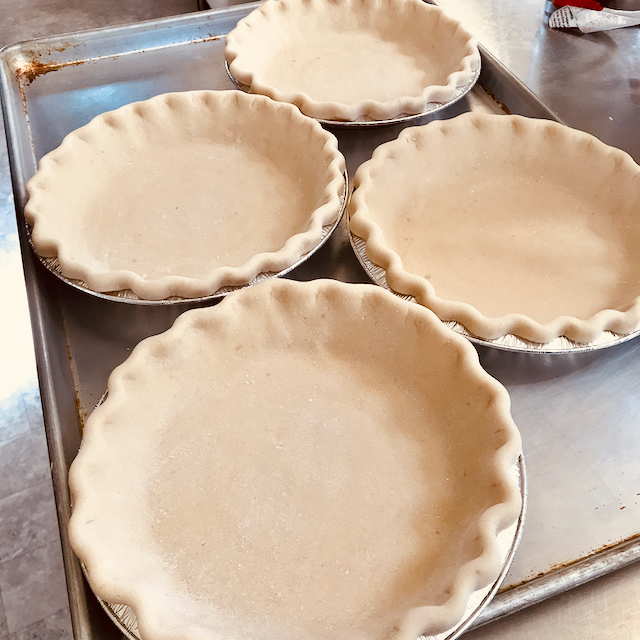 Four raw pie crusts on a tray